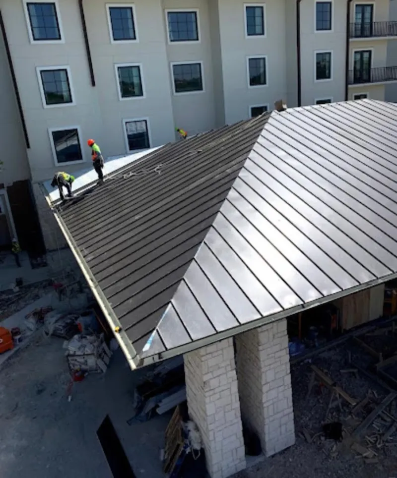 Crew installing standing seam metal roof panels on a commercial project in Shepherdsville